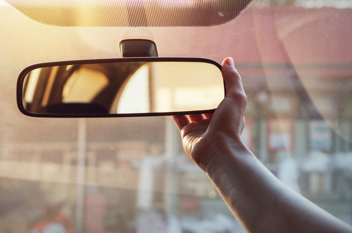 A hand adjusting the rear view mirror of a car